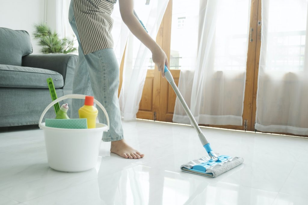 Young woman cleaning floor using mop at home.