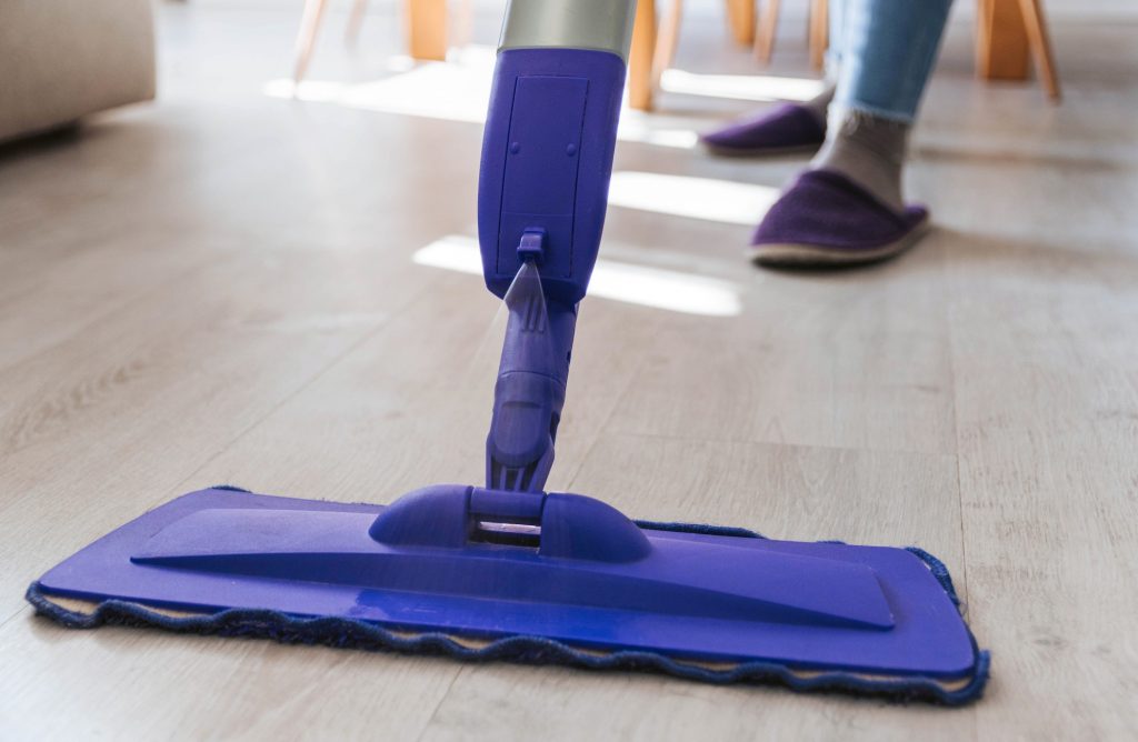 Close-up cropped image of floor mop, person cleaning floor, spring cleaning.